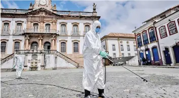  ?? — AFP photo ?? Members of a cleaning crew disinfect the streets around the Tiradentes Square in Ouro Preto, Minas Gerais state, Brazil against the new coronaviru­s, Covid-19.