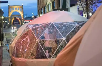  ?? Emily Matthews/Post-Gazette ?? People eat inside plastic “igloos” on Nov. 27 along Sixth Street outside the Miracle pop-up bar in Downtown.