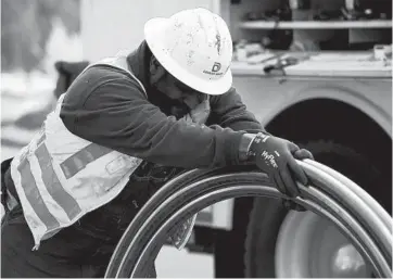  ?? ANDY CROSS/THE DENVER POST PHOTOS ?? Nick Downs uncoils copper pipe for lead service line replacemen­t in Denver in December 2019. Denver Water replaced 5,200 lead service lines last year and delivered more than 100,000 filters to residents.