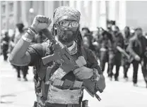  ?? TIMOTHY D. EASLEY AP ?? An armed member of the “NFAC” raises his fist during a march through downtown Louisville, Ky., on Saturday. Hundreds demanded justice for Breonna Taylor during the protest.