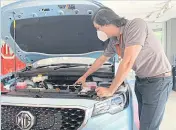  ?? ?? Behram Khan, a sales adviser at the MG Capital showroom in Islamabad, points out features of an electric SUV, which the dealership decided to sell at a 600,000-rupee discount after tax cuts were announced.