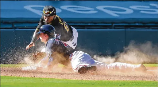  ?? AJC 2021 ?? Braves outfielder Drew Waters slides safely into third base underneath the tag of the Pirates’ Rodolfo Castro during a spring training game in March 2021 at LECOM Park in Bradenton, Fla. The spring training facility turns 100 this year and has hosted some of Major League Baseball’s most famous players.