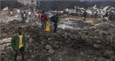  ?? Photo: Nampa/AFP ?? Ashes… Residents stand next to destroyed structures near smoulderin­g ashes early morning in Goma in the East of the Democratic Republic of Congo on 23 May, 2021 following the eruption of Mount Nyiragongo.