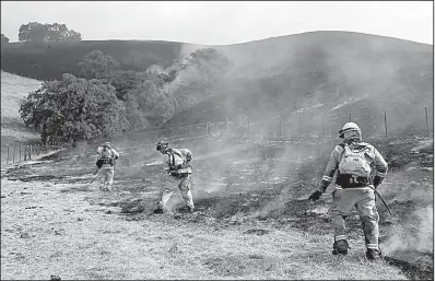  ?? The New York Times/JIM WILSON ?? Firefighte­rs work to contain a blaze Wednesday at a ranch in Bennett Valley in Sonoma County, Calif., before an expected increase in winds that would fan the flames.