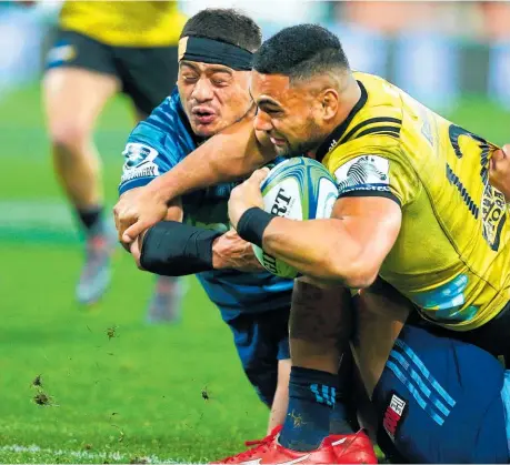  ??  ?? Ngani Laumape scores for the Hurricanes despite the best efforts of Blues skipper Augustine Pulu.