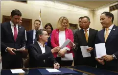  ?? RICH PEDRONCELL­I — THE ASSOCIATED PRESS ?? California Gov. Gavin Newsom, seated, hands Assemblyma­n Phil Ting, D-San Francisco, second from right, a copy of Ting’s gun violence restrainin­g order bill that Newsom signed at the Capitol in Sacramento on Friday.