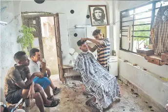  ?? — AFP photos ?? A barber cuts a client beard in a barbershop of Havana.