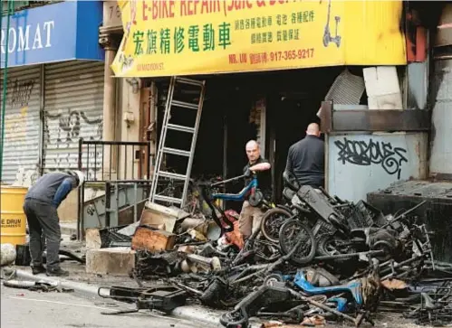  ?? LUIZ C. RIBEIRO FOR NYDN ?? Fire marshalls remove charred remains of e-bikes and batteries from Chinatown store in June. The Adams administra­tion and Council are working on measures to reduce deadly fires.