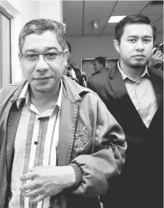  ??  ?? Azman being escorted by MACC officer to the Sessions Court. — Bernama photo