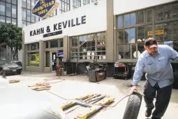  ??  ?? Guillermo Mendez changes a car tire at Kahn & Keville at 500 Turk St., which is under considerat­ion for an affordable housing developmen­t.