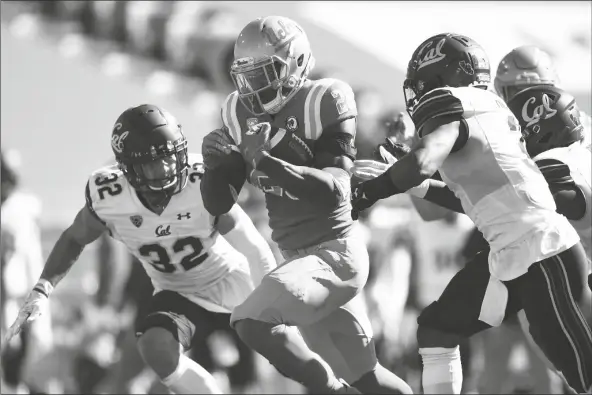  ?? ASSOCIATED PRESS ?? UCLA RUNNING BACK BRITTAIN BROWN (center) runs the ball for a touchdown past California safety Daniel Scott (left) and Elijah Hicks during the second half of a game against California in Los Angeles on Sunday.