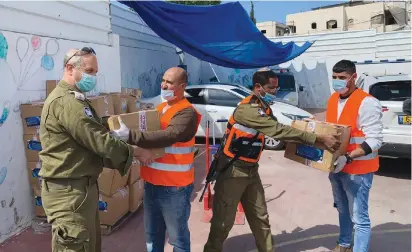  ?? (IDF) ?? COLONEL SHARON GAT and IDF soldiers in east Jerusalem, as they provide assistance for local families alongside Palestinia­n volunteers.