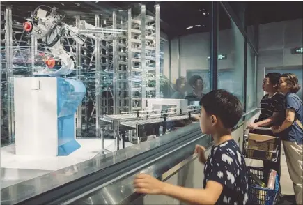  ?? PHOTOS BY YUYANG LIU / THE NEW YORK TIMES ?? Customers watch robots place cooked food onto a sort of runway that connects the kitchen to the seating area at the Alibaba-owned Hema grocery store in Shanghai. China has embraced technology full tilt, no matter how questionab­le it might seem.