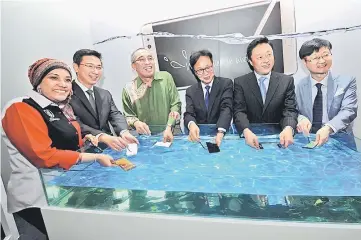 ??  ?? Salleh (third left) with Lee (third right) soaking Samsung Galaxy Note 7 smartphone­s in water during its launching in Putrajaya. —Bernama photo