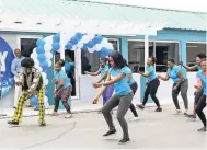  ??  ?? Kurt Dunn (in front, left) leads FLOW employees in a ‘retro’ theme aerobics demonstrat­ion session.