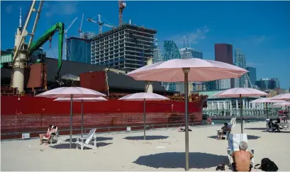  ?? NATHAN DENETTE THE CANADIAN PRESS ?? People practise physical distancing as they enjoy the hot weather at Sugar Beach in Toronto on Tuesday.