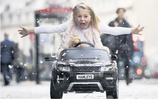  ??  ?? > A girl drives a Range Rover Evoque Ride-on electric car on Regents Street, London, as Hamley’s announced its top 10 toys for Christmas