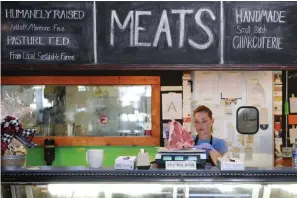  ?? Adam Robison/The Northeast Mississipp­i Daily Journal via AP ?? ■ Allison Wells, butcher and general manager at Neon Pig, weighs a block of meat in the meat market of Neon Pig.