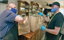  ?? Dan Watson/The Signal ?? (Above) El Trocadero Steak House owner Raul Bojorquez, left, checks the bags as Santa Clarita Grocery volunteer Bradley Grose picks up Mexican food meals prepared for the Feed the Fight program in Newhall on Thursday. (Below) Santa Clarita Grocery volunteer Susan Grose places the last of 44 meals prepared for the program by Newhall Refinery and El Trocadero Steak House into an SUV.