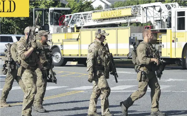  ?? SAUL LOEB / AFP / GETTY IMAGES ?? A police SWAT team moves into position after a shooting Thursday in Annapolis, Md. At least five people were killed when a gunman opened fire inside the offices of the Capital Gazette newspaper. Annapolis is about an hour east of Washington.