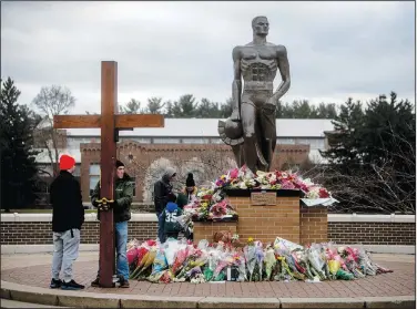  ?? (File Photo/AP/The Flint Journal/Jake May) ?? Dan Beazley of Northville Township holds a large wooden cross Wednesday as a crowd gathers at the Spartan Statue, where a makeshift memorial continues to build with flowers and keepsakes, at Michigan State University in East Lansing, Mich.