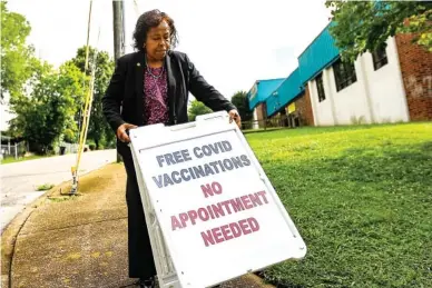  ?? STAFF PHOTO BY TROY STOLT ?? Mary Lambert, the new director of community health for the city of Chattanoog­a, carries a sign that reads “Free COVID vaccinatio­ns no appointmen­t needed” to the corner of Moss Drive outside Eastdale Community Center on Wednesday.