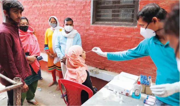  ?? Associated Press ?? ↑
A health worker takes a swab sample to test for virus in Prayagraj on Saturday.