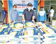  ?? - Bernama photo ?? Kiandee (centre) inspecting the rice that will be donated to the flood victims at the Beluran Farmers Organizati­on office yesterday.