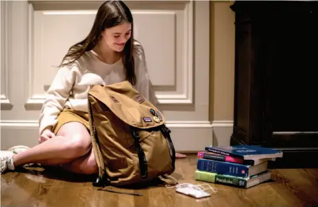  ?? PHOTO BY J. LAWLER DUGGAN FOR THE WASHINGTON POST ?? Bethesda-Chevy Chase High School junior Lee Schwartz sits with her backpack alongside the textbooks she doesn’t bring to school or keep in a locker. “We’re losing some of the classic culture,” she said.