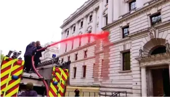  ??  ?? Demon-spray-tion: Eco-activists take aim at the Treasury from the fire truck