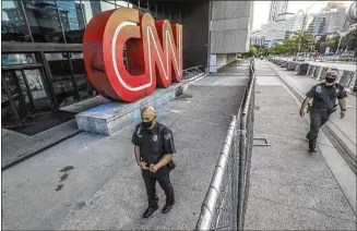  ?? JOHN SPINK / JSPINK@AJC.COM ?? Security guards patrol the front of CNN Center where a fence blocked the perimeter of the building June 1 after vandals smashed windows and left graffiti during protests in Atlanta over recent incidents of police violence across the country..