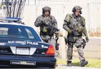 ?? DENIS POROY/ASSOCIATED PRESS ?? San Diego Police SWAT officers walk down the street after entering a house with a possible suspect inside on Friday in San Diego.