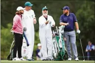  ?? David Cannon / Getty Images ?? Tommy Fleetwood, left, and Shane Lowry, right, and their caddies Ian Finnis and Brian Martin look on during a practice round prior to the Masters.