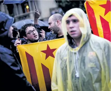  ?? PAU BARRENA/GETTY IMAGES ?? Men hold pro-independen­ce Catalan flags during a protest of the arrest of two Catalan separatist in front of the Spanish Government Delegation in Barcelona on Thursday.