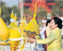  ?? PATIPAT JANTHONG ?? A woman presents a ‘phan phum’ offering before a portrait of His Majesty King Bhumibol Adulyadej The Great.