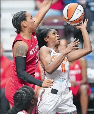  ?? SARAH GORDON/THE DAY ?? Connecticu­t Sun guard Nia Clouden (11) puts up a basket from under the Atlanta Dream’s Asia Durr during a WNBA game on June 15 at Mohegan Sun Arena.