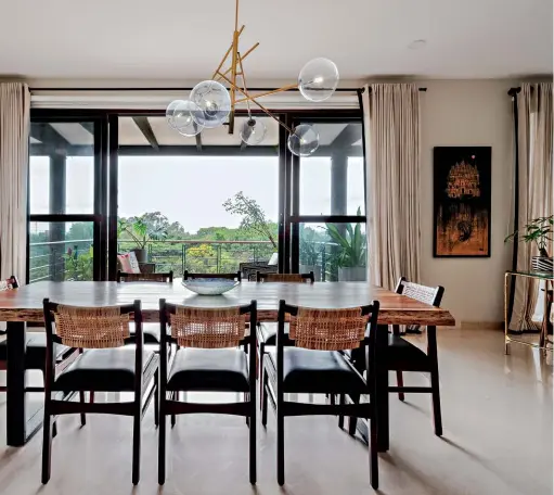  ??  ?? SPACE CRAFT The large dining area framed by a raw edge dining table and a minimal branch chandelier opens to a view of the terrace and green beyond (above); the homeowner Pavitra Shankar (left)