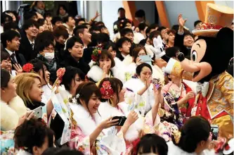  ??  ?? 20-year-old women draped in traditiona­l kimonos and men clad in business suits are celebrated by Mickey Mouse (right) during their "Coming-of-Age Day" ceremony.