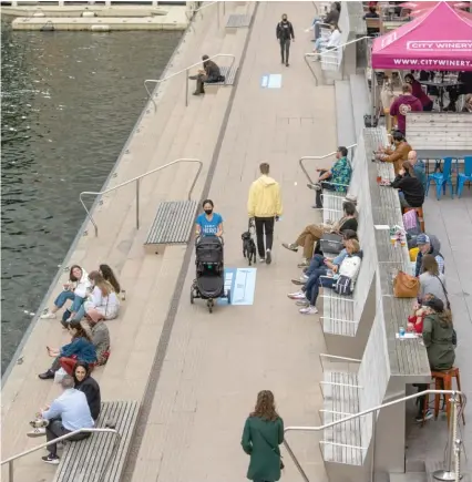  ?? TYLER LARIVIERE/SUN-TIMES ?? People relax at City Winery on Friday along the Chicago Riverwalk as others walk by on the trail.