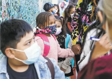  ?? Amy Osborne / Special to The Chronicle ?? Above: Children wait to check in for the first day of inperson classes at Bryant Elementary School in the Mission.