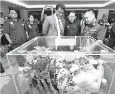  ??  ?? Dr Jayakumar (fourth left) looking at the confiscate­d products that people had attempted to bring in and out of the country, displayed during the Sabah Biosafety Awareness Seminar yesterday.