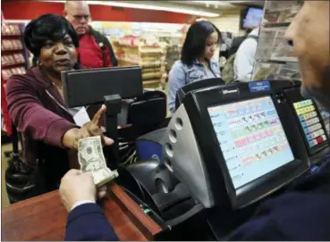  ?? BEBETO MATTHEWS — THE ASSOCIATED PRESS ?? Annette Gray, left, from Valley Stream, N.Y., buys lottery tickets Friday in New York. The estimated jackpot for Friday’s Mega Millions drawing has soared to $1 billion. Gray said it’s about “a dollar and a dream, but I spent ten today.”