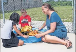  ??  ?? Noelle Speas, 7, left; Conner Cummins, 11; and personal aid Chrissy Johnson play with trucks in a sandbox during a lesson break.