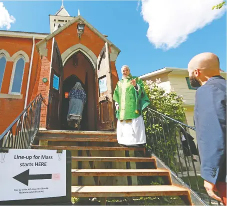  ?? GAVIN YOUNG ?? Father Robert Bengry greets parishione­rs as they arrive for mass at St. John the Evangelist Roman Catholic Church in Inglewood on Sunday. Though places of worship have been given the green light to reopen in Alberta, many are keeping their doors closed over safety concerns.