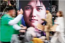  ?? — AFP photo ?? People walk past an advertisem­ent with a picture of Shohei Ohtani in Tokyo.