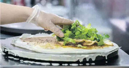  ?? PHOTOS: DAVE SIDAWAY ?? Jian bing guo is a savoury white flour batter crêpe with an egg spread over it, filled with soybean paste and fried won ton. It’s then folded together and eaten by hand. It’s best when eaten immediatel­y, when fresh and crispy, thus doesn’t lend itself...