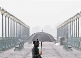  ?? Carlos Avila Gonzalez / The Chronicle ?? A man walks along the Embarcader­o in San Francisco as a storm drops several inches of rain on the region. The rain is expected to extend into the morning commute before subsiding at 10 a.m. The rest of the week should be dry.