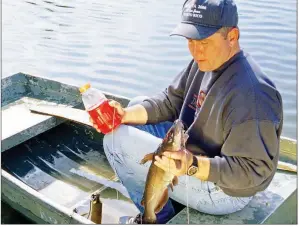  ?? KEITH SUTTON/CONTRIBUTI­NG PHOTOGRAPH­ER ?? Alex Hinson of Paron lands a nice channel cat caught using an empty drink jug for a float. Painting jugs so they are brightly colored helps anglers see them better when several are used.