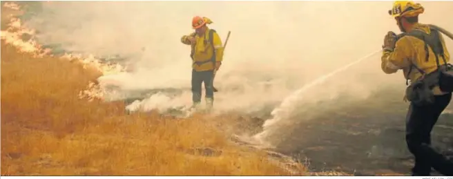  ?? MIKE NELSON / EFE ?? Dos bomberos intentan sofocar las llamas el pasado sábado en la localidad california­nana de Malibú.