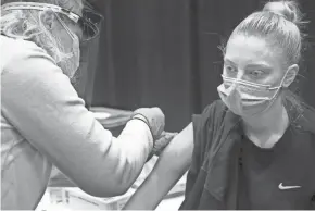  ?? ANGELA PETERSON / MILWAUKEE JOURNAL SENTINEL ?? Morgan Snyder, 22, of Milwaukee, a behavioral health technician, gets the COVID-19 vaccine from registered nurse Nancy Burns at the Wisconsin Center on Thursday. “I’m excited about getting the shot. I’m hoping it will help relieve some of the anxiety,” she said. She was among the eligible city employees who were getting the first vaccine. She and others will return in a few weeks for their second dose.